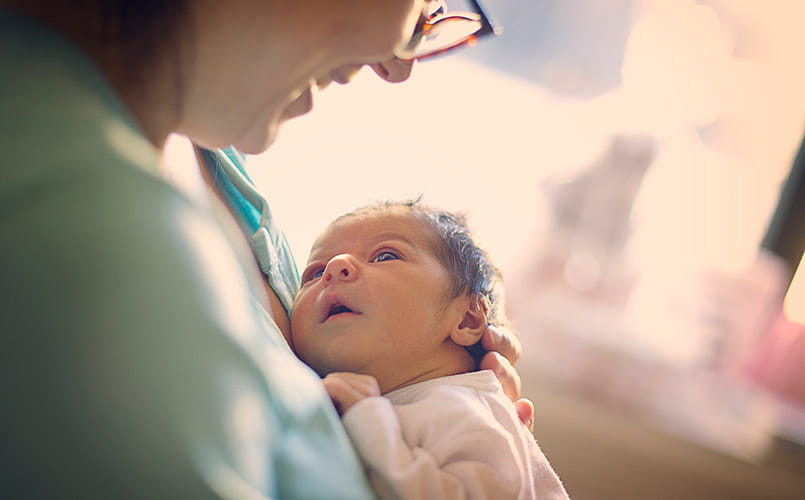 A mom smiling at her newborn in hospital
