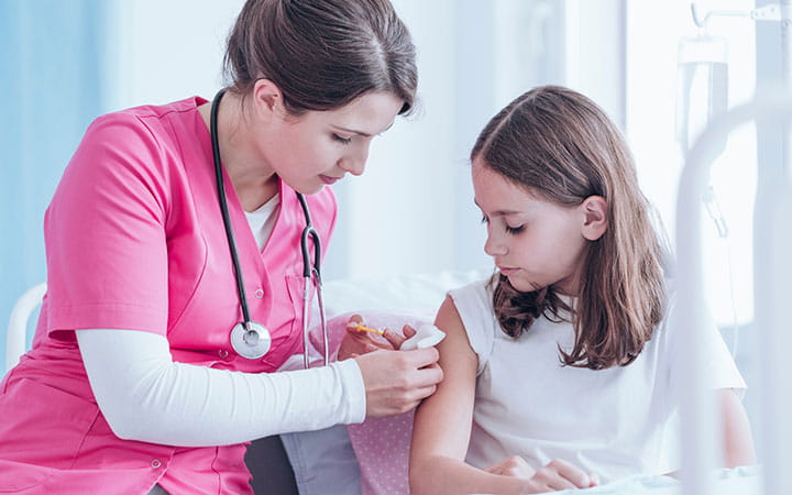 Doctor giving a girl a shot in the shoulder