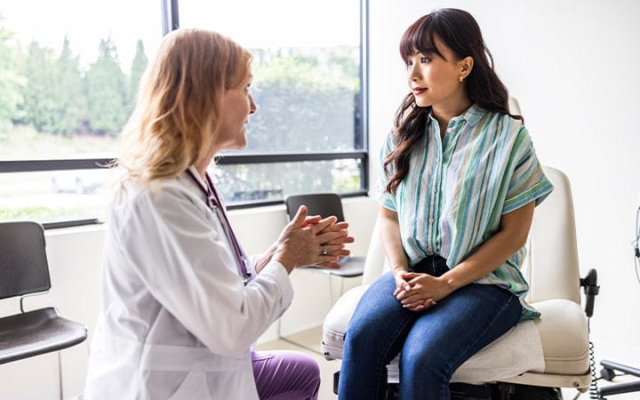 A female doctor talking with a young woman in an exam room