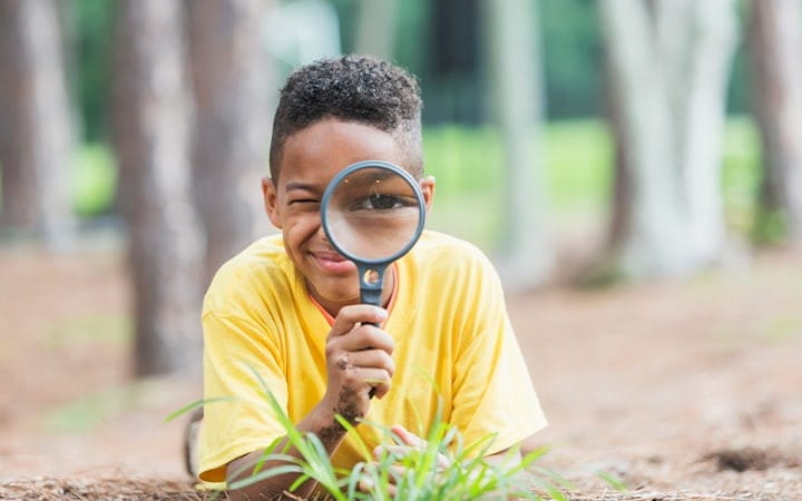 Child looks through magnifying glass