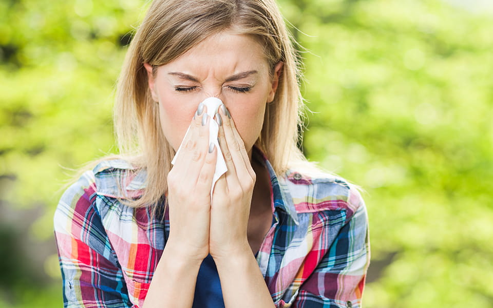 Young woman sneezing into tissue