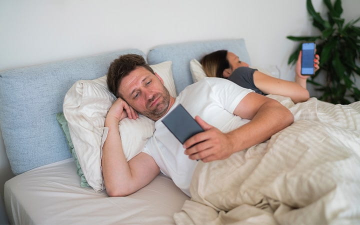 Couple on phones in bed