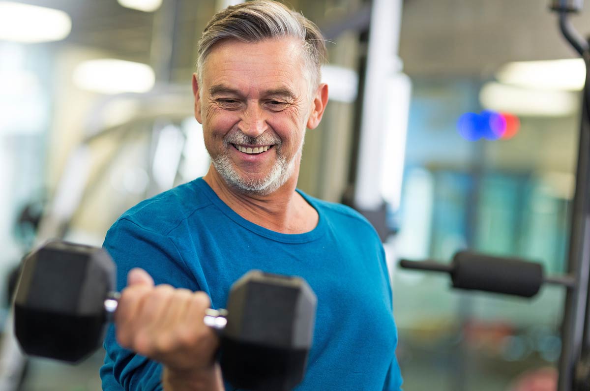 smiling older man lifting dumbbell