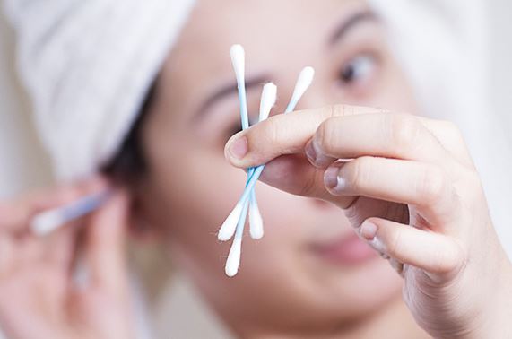 woman with towel wrapped head holding cotton swabs