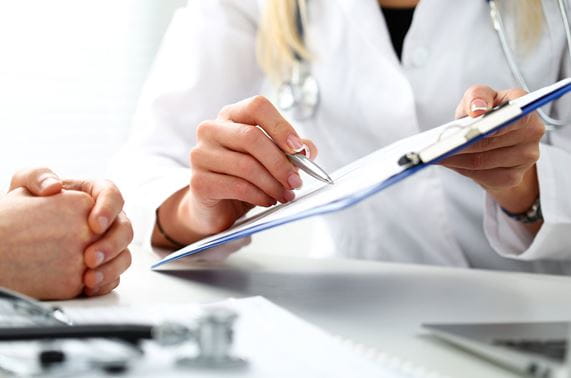doctor uses pen to point to clipboard