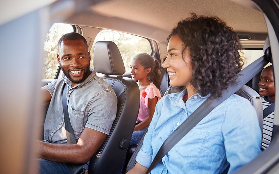 Young family in a car on a road trip smiling