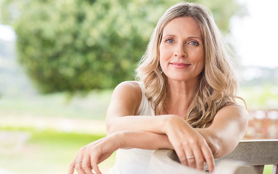 Happy woman relaxing on bench in the lawn