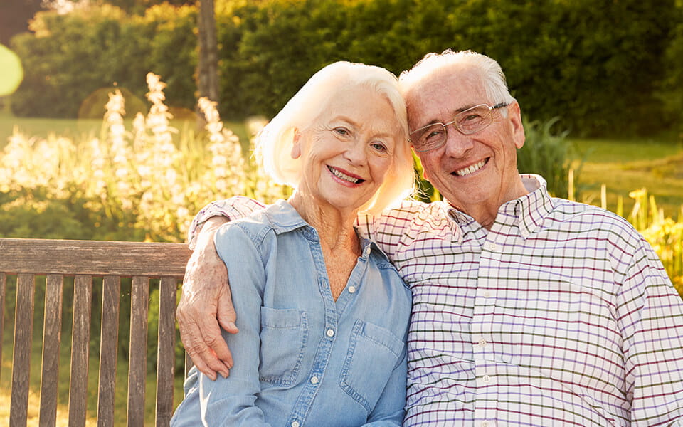 Senior couple sitting on garden bench in evening sunlight