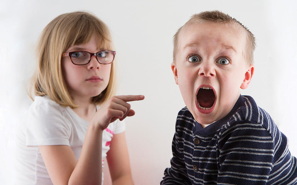 Boy is caught by sister and is now in trouble and making a funny face
