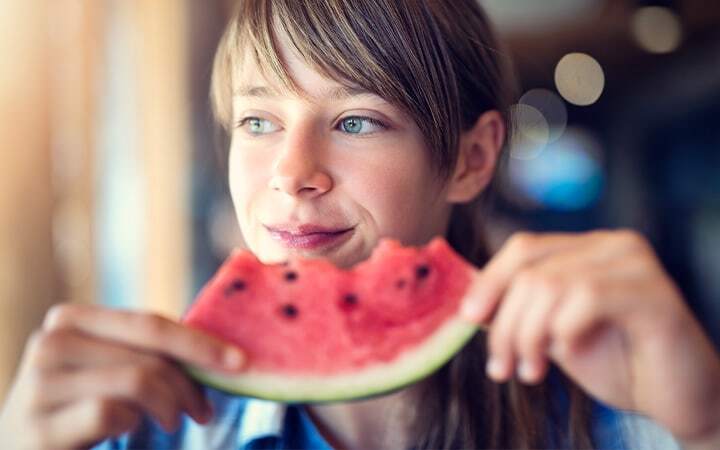 Teen eating slice of a watermelon