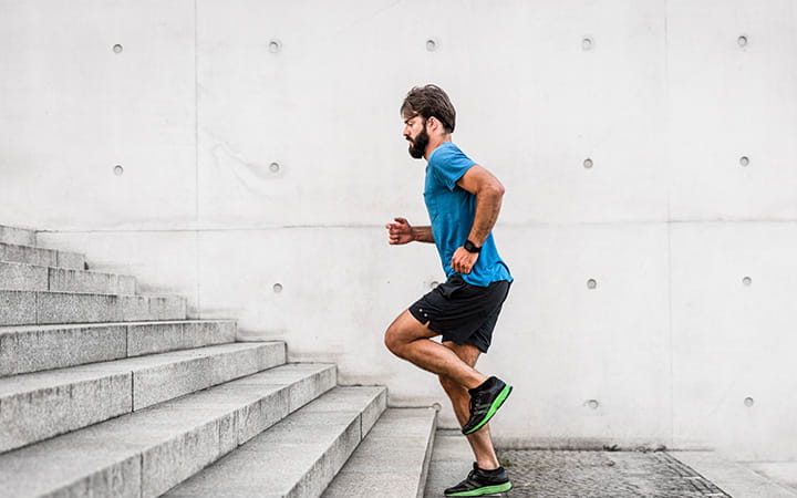 A sporty man running up steps in an urban setting