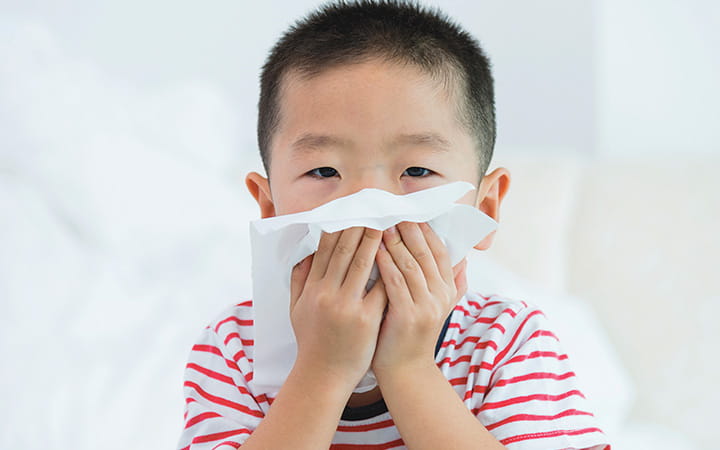 young child blowing his nose