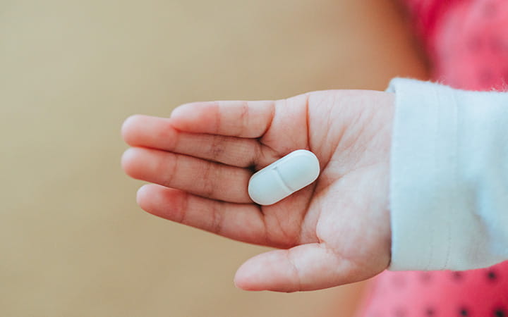 childs hand holding pill