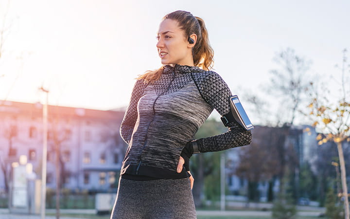 young woman runner stretches her back