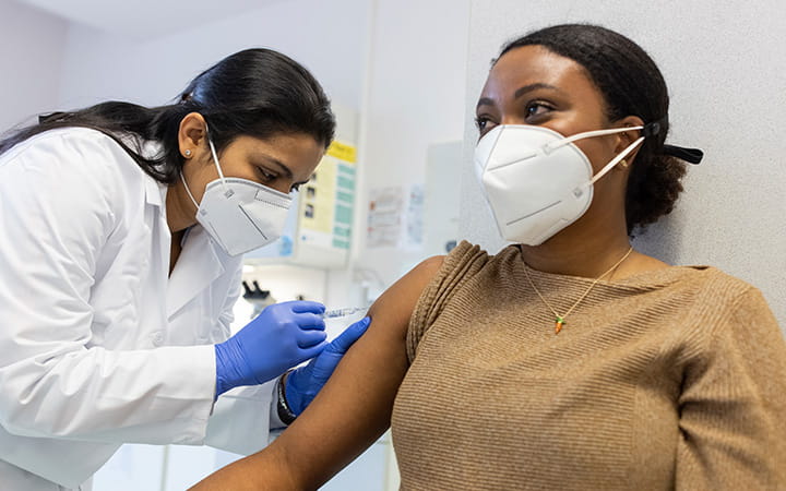 masked woman receiving covid vaccine