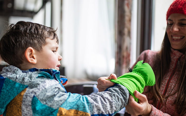 woman helping boy put on mittens