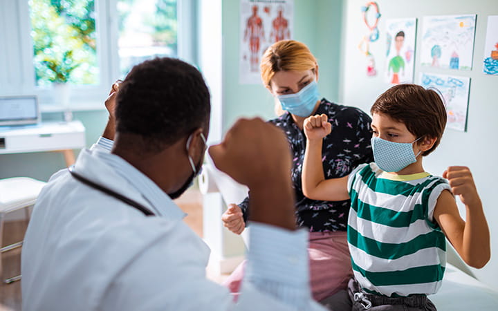 child flexing arm muscles for doctor