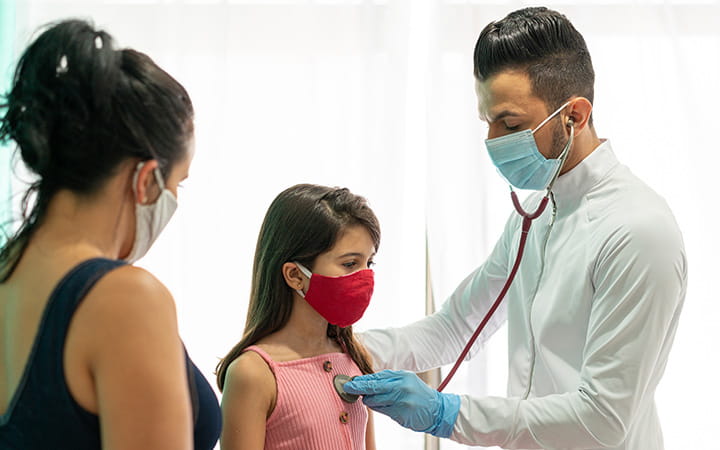 doctor listens to girl's heart as mother stands nearby