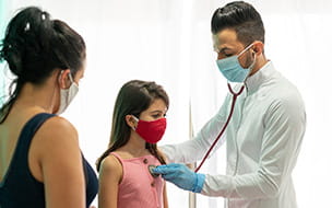 doctor listens to girl's heart as mother stands nearby