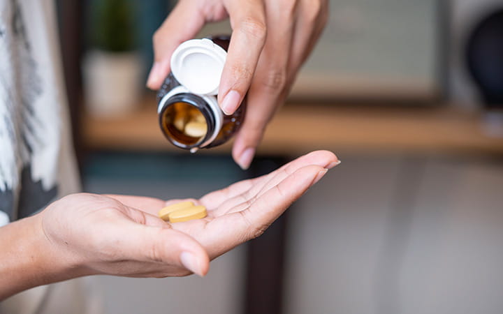 hand pouring pills from a bottle into another hand