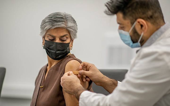 doctor putting bandaid on patient upper arm