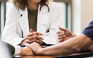 A couple holds hands as a urologist discusses an upcoming procedure