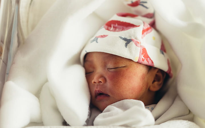 swaddled newborn wearing cap