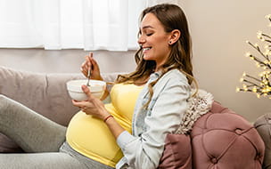 pregnant woman digging into a deep bowl with a spoon