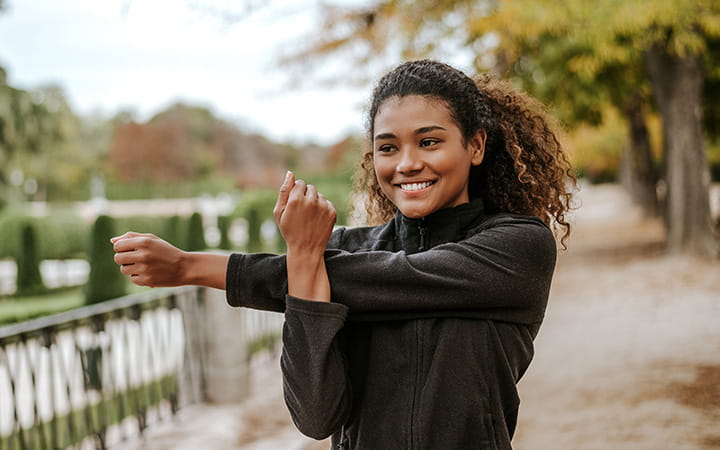 young woman stretching her arm by pulling it across her chest