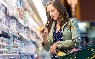 woman reading labels on yogurt containers at the grocery store