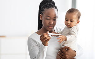 mother holding a baby and looking at a thermometer