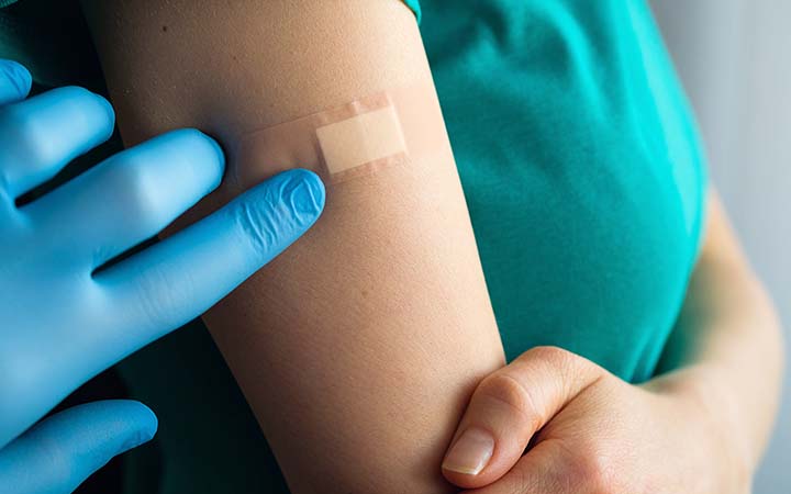 sterile gloved hand pressing down bandage on arm