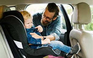 A smiling toddler in his car seat