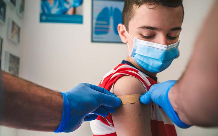 young boy getting an adhesive bandage after a shot
