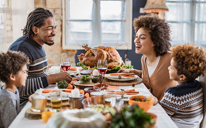 family of four gathered around square thanksgiving table
