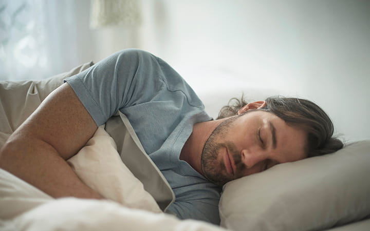 young bearded man lying on his side in bed