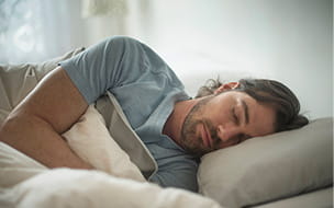 young bearded man lying on his side in bed