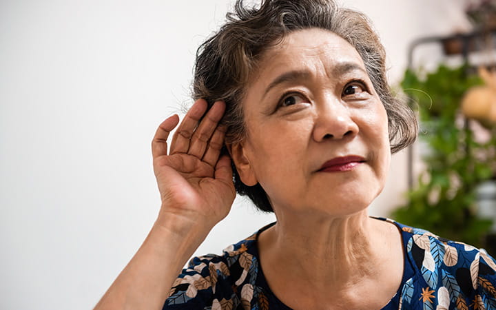 older woman with hand cupped to her ear