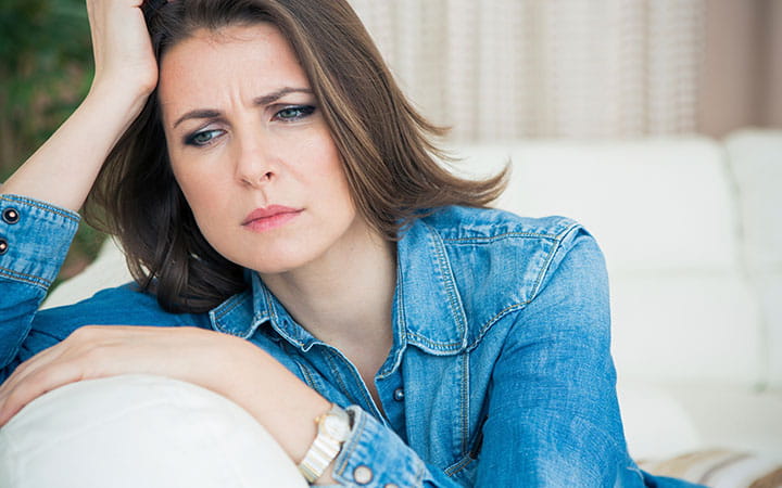 Upset mid-age woman sitting on sofa