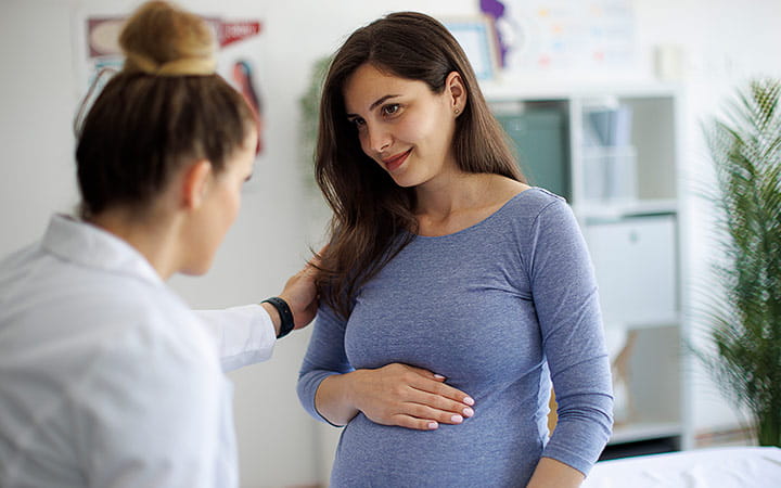 A smiling pregnant woman having a consultation with a doctor