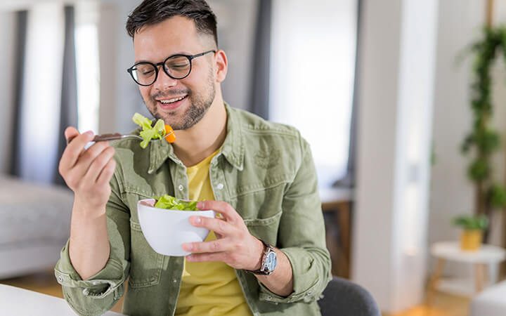 A happy young man eating a healthy salad
