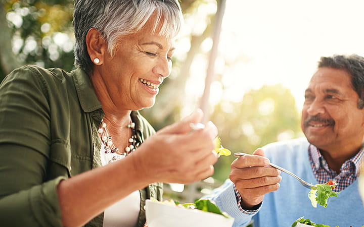A happy older couple enjoying a healthy lunch together outdoors