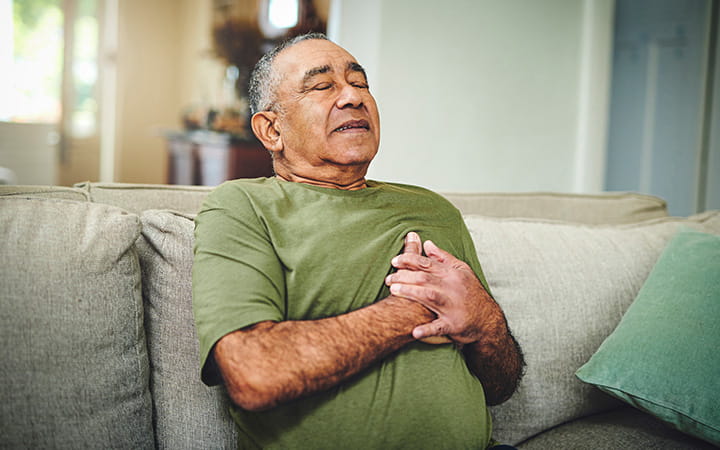 A senior man holds his chest in pain