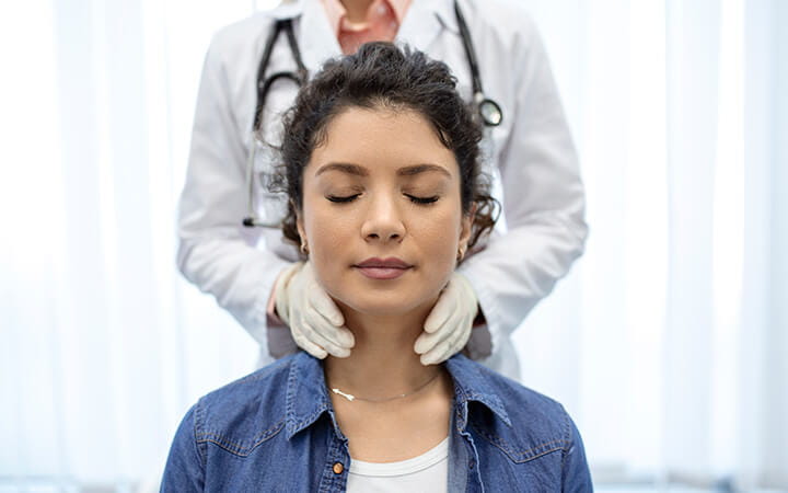 Endocrinologist examining throat of young woman