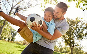 Father and son playing soccer in park together
