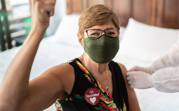 Portrait of a senior woman using 'Get vaccinated' sticker celebrating after being vaccinated at home