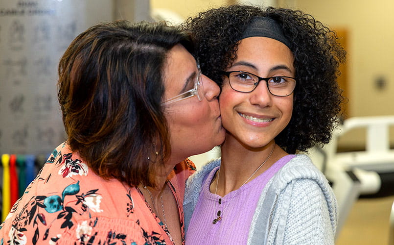 Eliana gets a kiss on the cheek from her mother