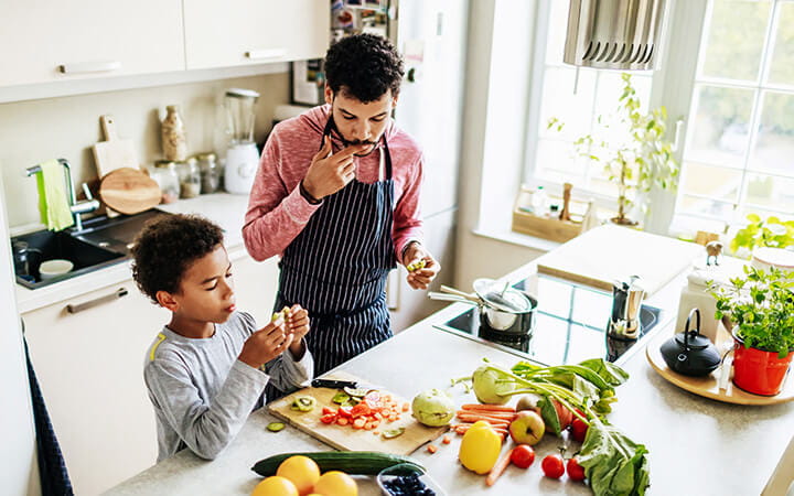 A dad spending some time with his son, snacking while they prepare some lunch together
