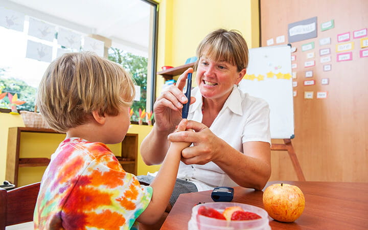 A nurse shows a diabetic child how to test his blood