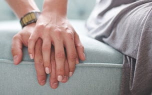 A man and woman holding hands while sitting on a couch